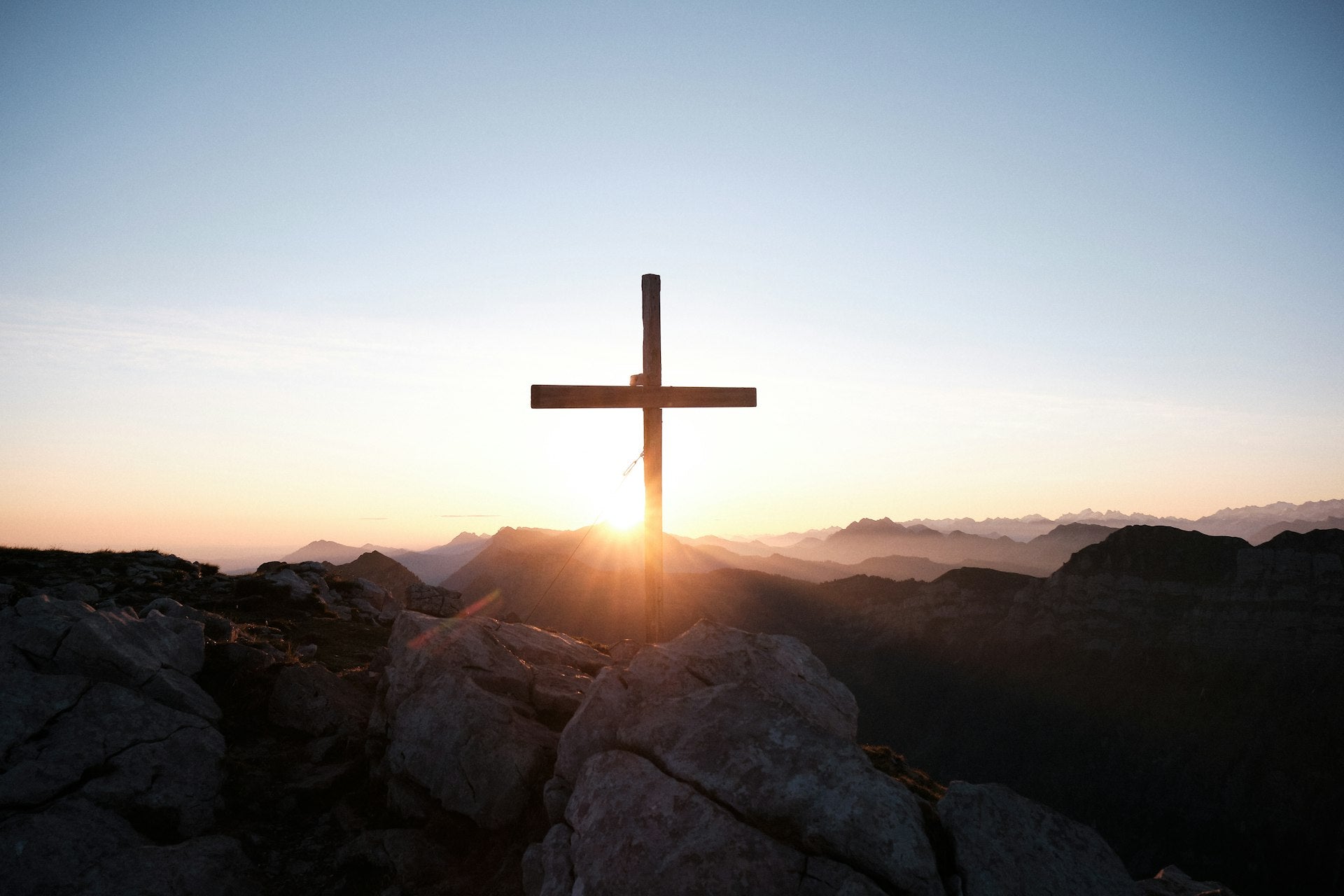 Croix en silhouette au lever du soleil dans les montagnes